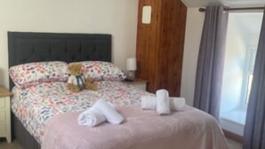 A bedroom with a bed, a teddy bear, and a wooden headboard.