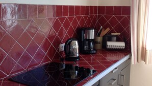 Eine Küche mit roter Fliesenrückwand, einem schwarzen Wasserkocher, einer Kaffeemaschine und einem Messerblock.