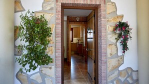 A hallway with a stone archway, a wooden door, and a hanging flower arrangement. - Apartment with pool and spectacular views, ideal for families (IZNAJAR)