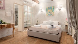 Un dormitorio con una cama, una mesita de noche, una lámpara de pared y una puerta que da a otra habitación.