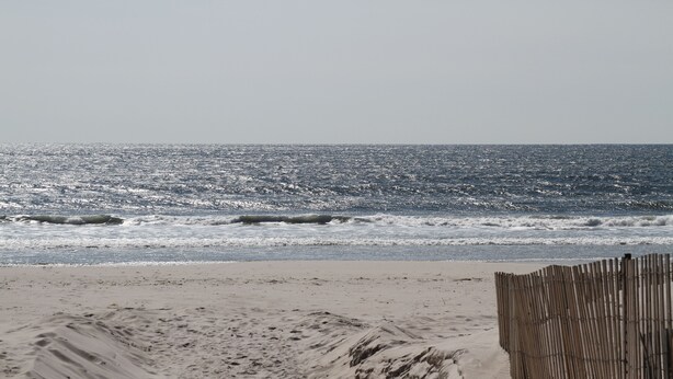A sandy beach with a wooden fence and the ocean in the background. - Cozy Studio in Long Beach / EAB (East Atlantic Beach)
