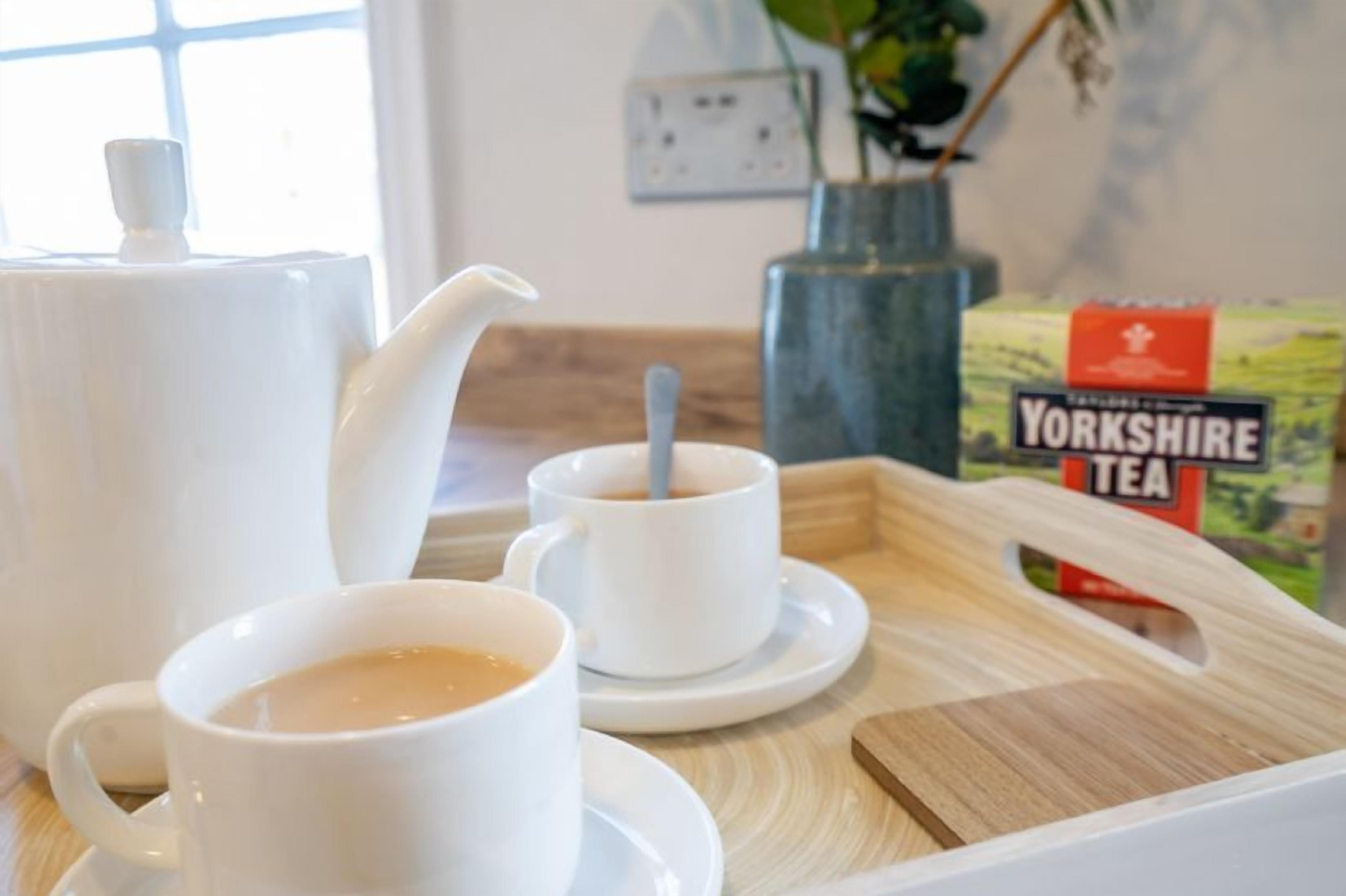 A tray with a teapot, two cups of tea, and a box of Yorkshire tea.