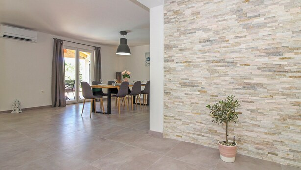 A spacious dining area with a modern table and chairs, a potted plant, and a stone wall. - Natascha in Pamići (Haus für 6 Personen) (Žminj)