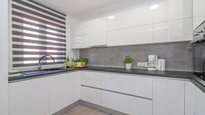 A modern kitchen with white cabinets, a black countertop, a built-in oven, and a coffee maker. - Natascha in Pamići (Haus für 6 Personen) (Žminj)
