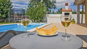 A poolside table with two glasses of white wine and a plate of melon slices. - Natascha in Pamići (Haus für 6 Personen) (Žminj)