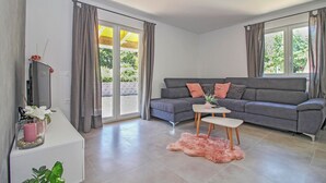 A modern living room with a grey sofa, a small white table, and a pink furry rug. - Natascha in Pamići (Haus für 6 Personen) (Žminj)