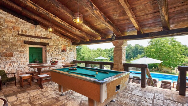 A pool table in a stone-walled room with a wooden ceiling, a green door, and a view of a swimming pool outside. - Holiday house Stara Hiža * large garden, private pool, free WiFi (Sveti Petar u Šumi)