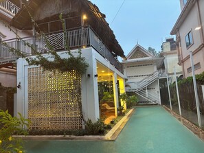 Un edificio residencial con balcón, techo de paja y zona de piscina.