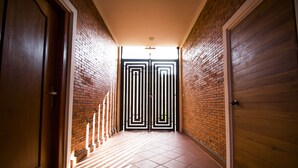 A hallway with a tiled floor, brick walls, and a double door at the end. - Koki Tree (Siem Reap)