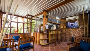 A restaurant with wooden furniture, a brick wall, and a TV screen. - Koki Tree (Siem Reap)