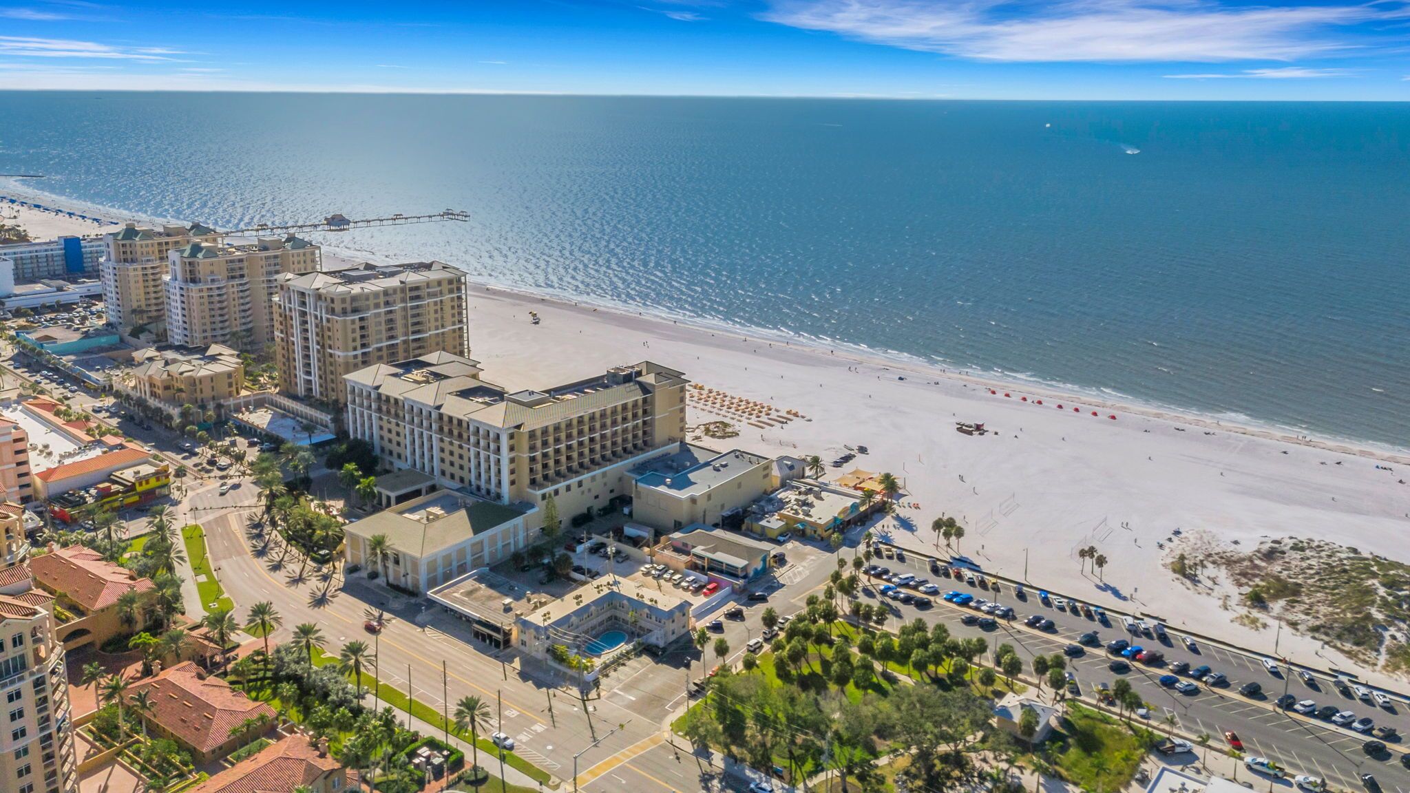 Ein Hotel an der Küste mit mehreren Gebäuden, einem Strand und einem Parkplatz.