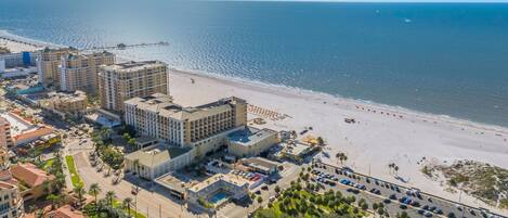 Ein Hotel an der Küste mit mehreren Gebäuden, einem Strand und einem Parkplatz.
