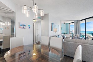 Ein modernes Hotelzimmer mit Essbereich, einer Couch mit Blick und einem großen Fenster zum Strand.