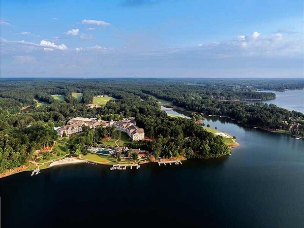 An aerial view of a lakeside resort with multiple buildings, a dock, and surrounding forested areas.