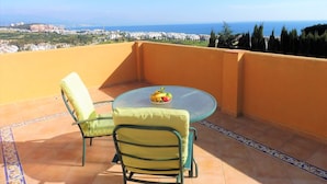 A balcony with a table and two chairs, overlooking a coastal cityscape. - luxury villa for 8 persons with private pool, panoramic views, WIFI (Manilva)