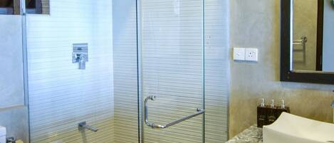 A bathroom with a glass-enclosed shower, a marble sink, and a toilet.