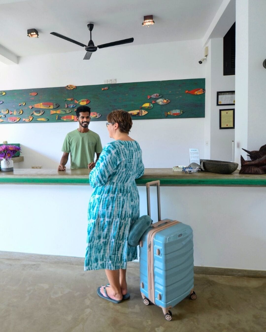 A reception area with a counter, a ceiling fan, and a wall with a fish mural.