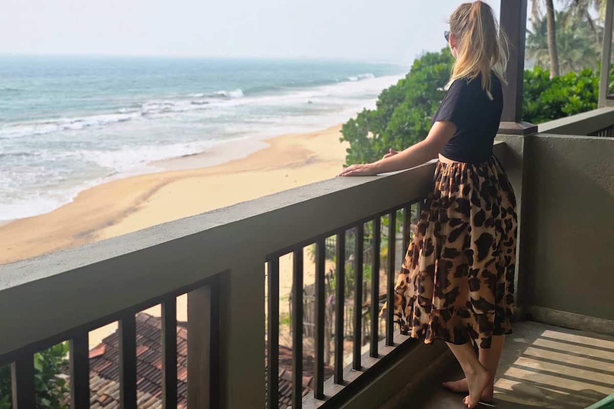 A balcony with a view of the beach and ocean.