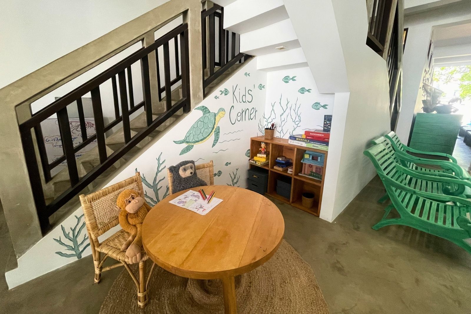 A children's play area with a wooden table, wicker chairs, and a green bench.