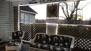 A covered outdoor seating area with wicker furniture and a sign reading "The Sports Cage". - The Canal Riverfront Getaway (Columbia)