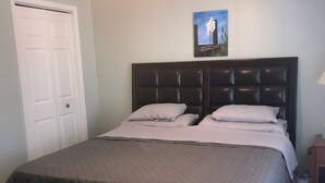 A bedroom with a bed, a door, a ceiling fan, a nightstand, and a picture on the wall. - The Canal Riverfront Getaway (Columbia)