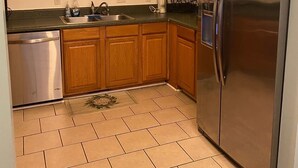 A kitchen with wooden cabinets, a stainless steel refrigerator, and a dishwasher. - The Canal Riverfront Getaway (Columbia)
