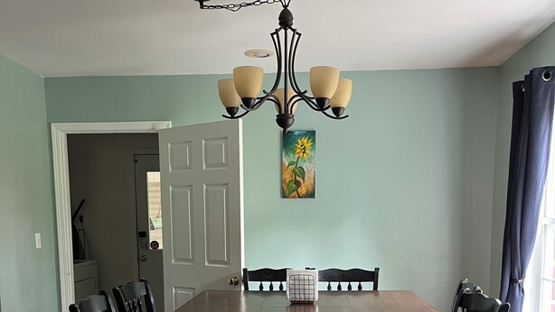 A dining room with a wooden table and chairs, a chandelier, and a painting on the wall. - The Canal Riverfront Getaway (Columbia)