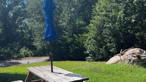 A wooden picnic table with a blue umbrella in a grassy outdoor area. - The Canal Riverfront Getaway (Columbia)