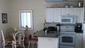 Un espacio habitable compacto con kitchenette, una zona de comedor con mesa y sillas, y un sofá.