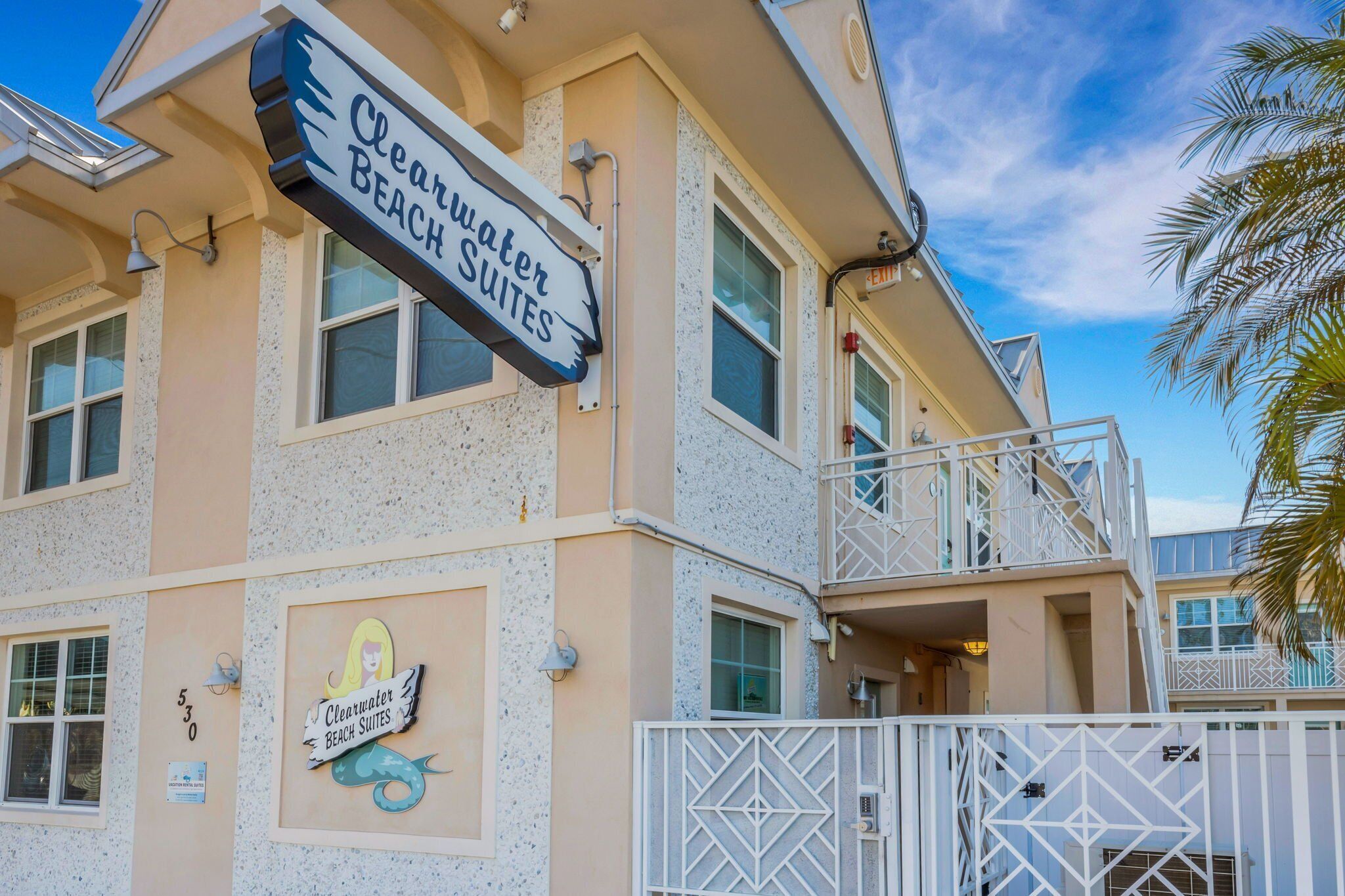 A building with a sign for 'Clearwater Beach Suites' and a mermaid logo.