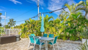 A patio with a table and chairs, surrounded by palm trees and a fence. - Cute beach condo with heated pool, steps to the sand ➠ CBS 204 (Clearwater)
