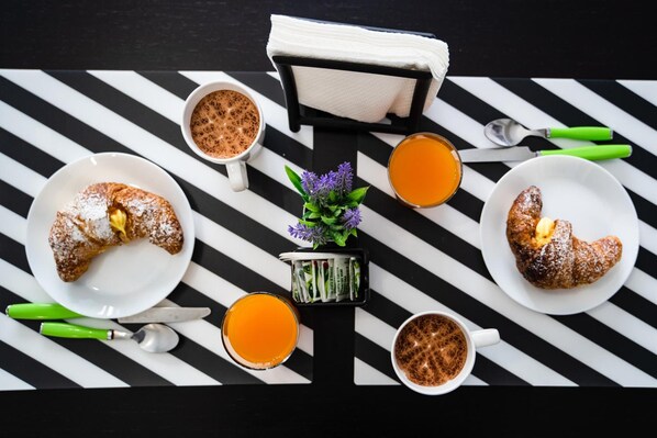 A breakfast setup with croissants, coffee, and orange juice on a striped table. - Le Due Sicilie Bed & Breakfast (Lascari)
