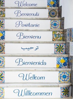 A staircase with steps labeled in multiple languages, including English, Italian, Polish, Spanish, French, and German, welcoming guests. - Le Due Sicilie Bed & Breakfast (Lascari)
