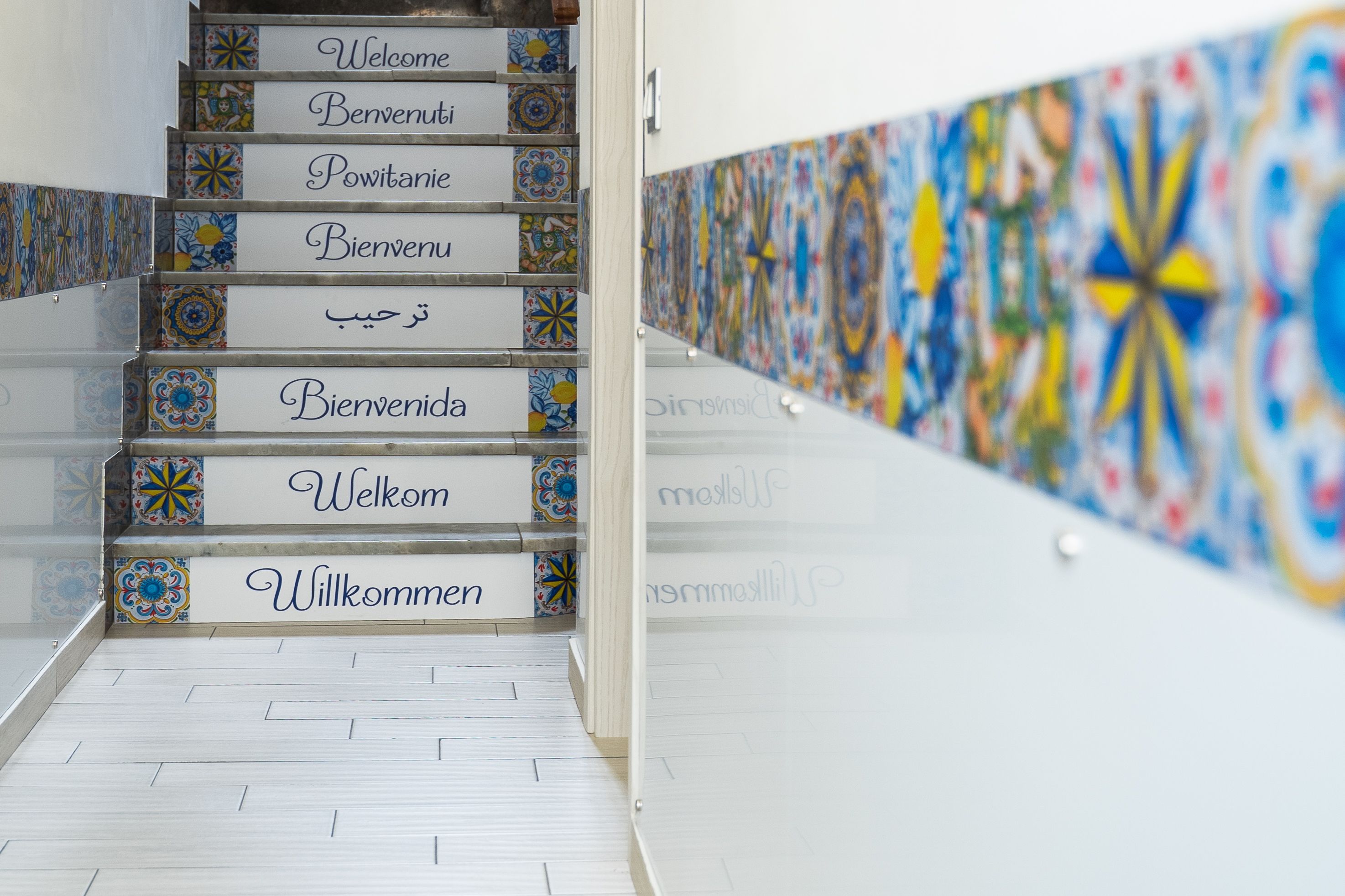 Una escalera con letreros de bienvenida multilingües en varios idiomas.