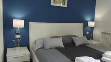 A neatly made bed with grey and white bedding, two bedside tables with lamps, and a framed map on the wall.