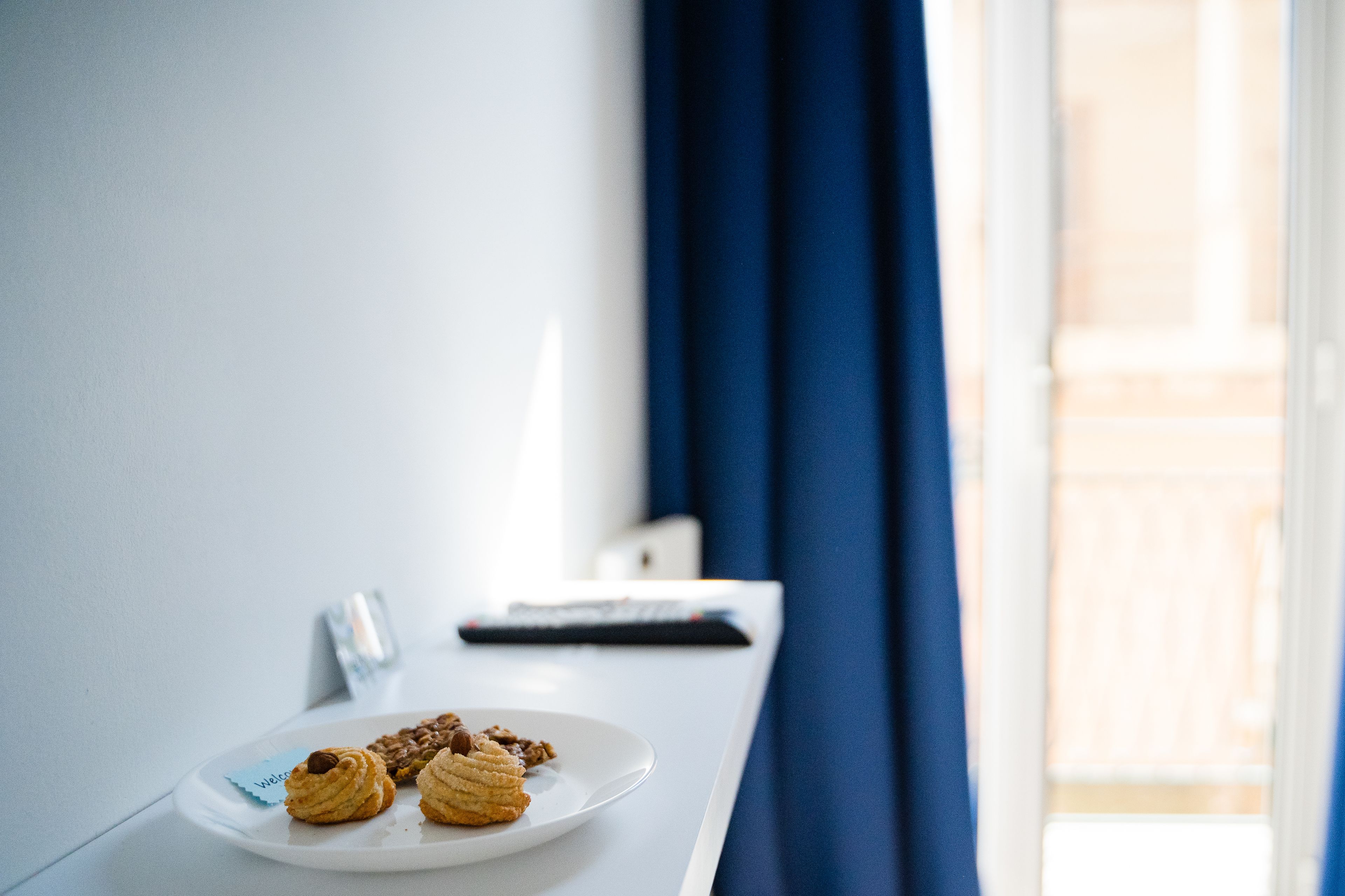 A white table with a plate of cookies and a remote control.