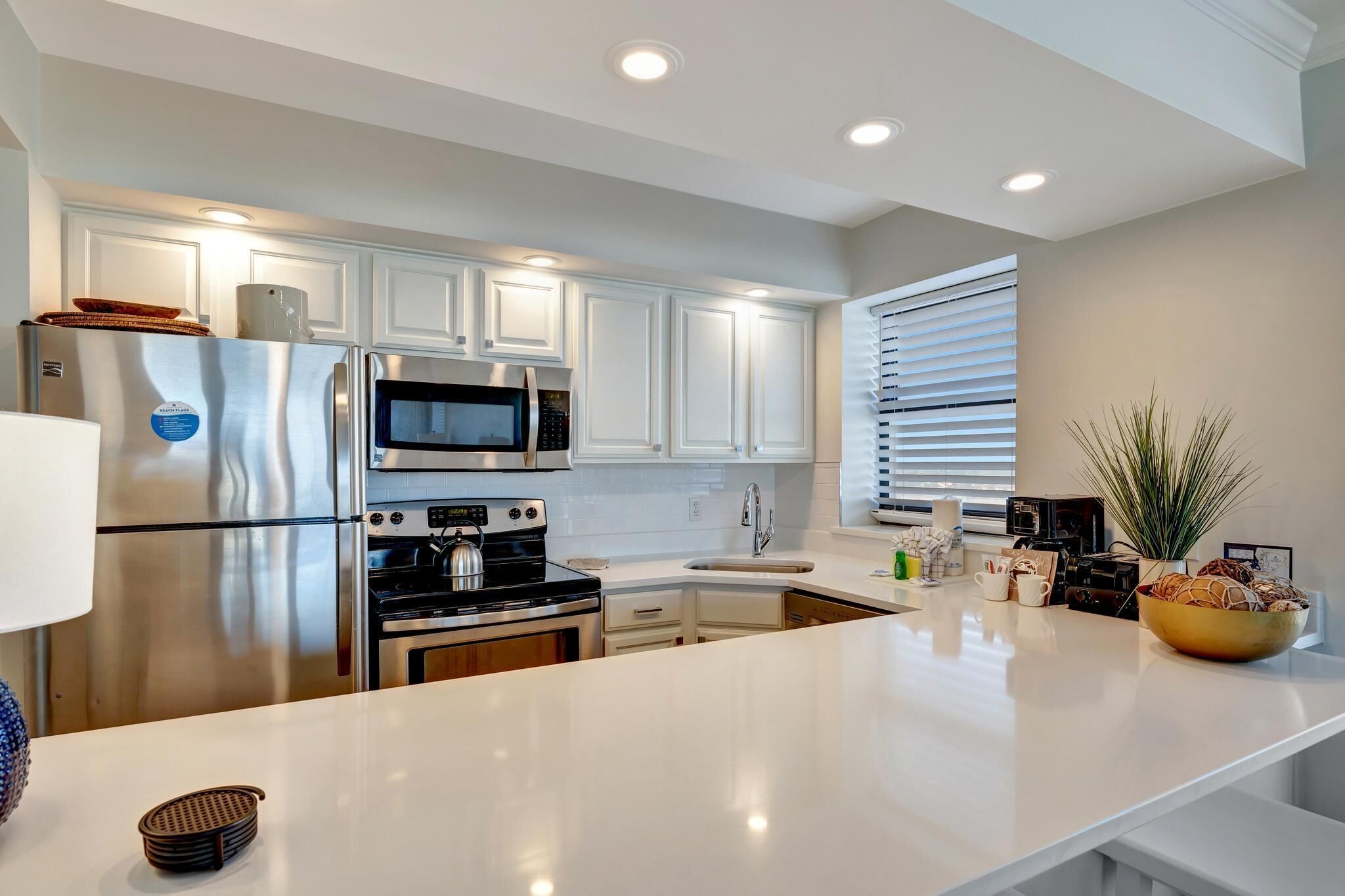 A modern kitchen with white cabinets, stainless steel appliances, and a central island.