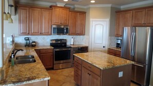 A kitchen with wooden cabinets, stainless steel appliances, granite countertops, and a tiled backsplash. - "As Good As It Gets" Beautiful Beach Front House! (Surfside Beach)