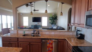 A kitchen with granite countertops, wooden cabinets, a dishwasher, and a ceiling fan. - "As Good As It Gets" Beautiful Beach Front House! (Surfside Beach)