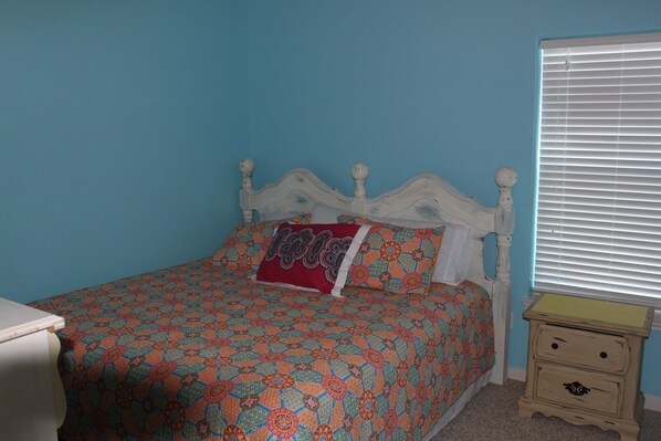 A bedroom with a bed, a nightstand, and a window with blinds. - "As Good As It Gets" Beautiful Beach Front House! (Surfside Beach)