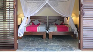A double bed with a canopy, two bedside tables, and a stone-tiled floor.