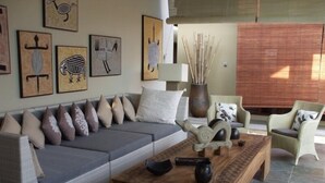 A modern living room with a grey sofa, a wooden coffee table, and a variety of decorative items including wall art and a vase with sticks.