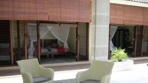 A room with a bed, a window with a view, and a table with vases.