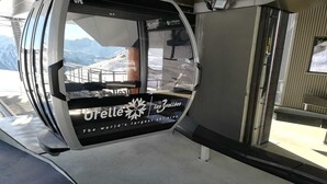 Cabina de telesilla con la marca 'Orelle Les Vallées' y vistas a un paisaje montañoso nevado.