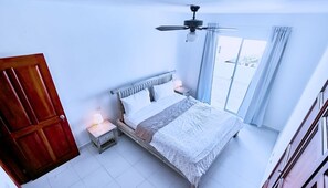 A bedroom with a bed, bedside lamps, a ceiling fan, and a view of the outside. - Los Corales Beach Village - Your private paradise - 2BR first floor - LT#D2b2 (Bávaro)