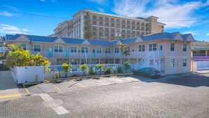 Ein mehrstöckiges Hotel mit Balkonen, einem Parkplatz und blauem Himmel.