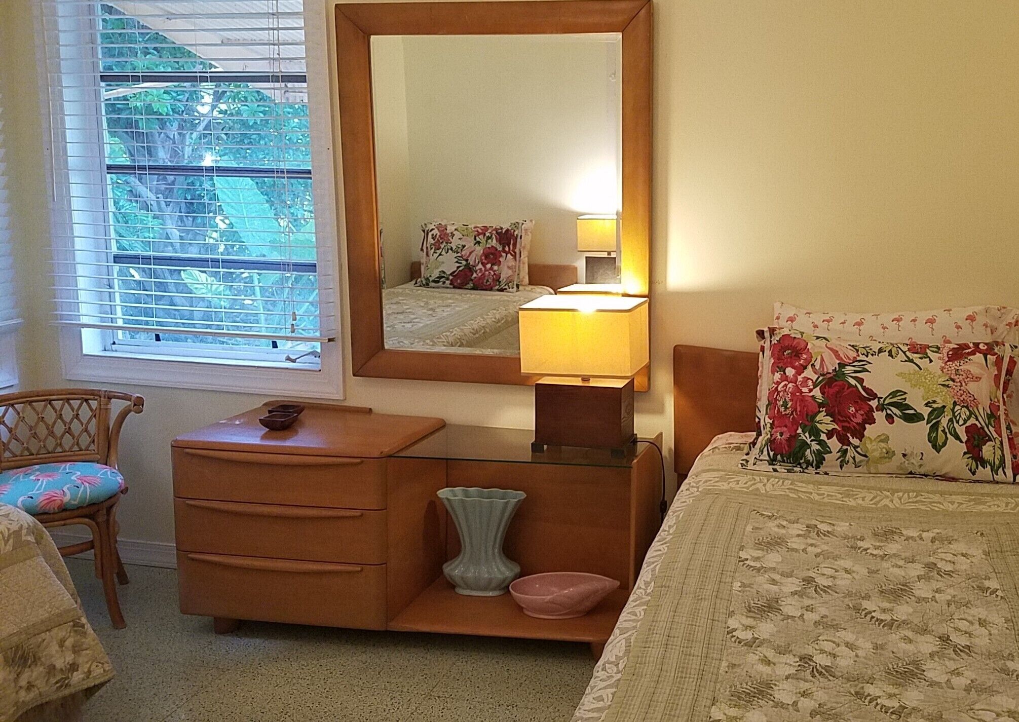 A bedroom with a bed, a dresser, a mirror, a window with blinds, and a chair.
