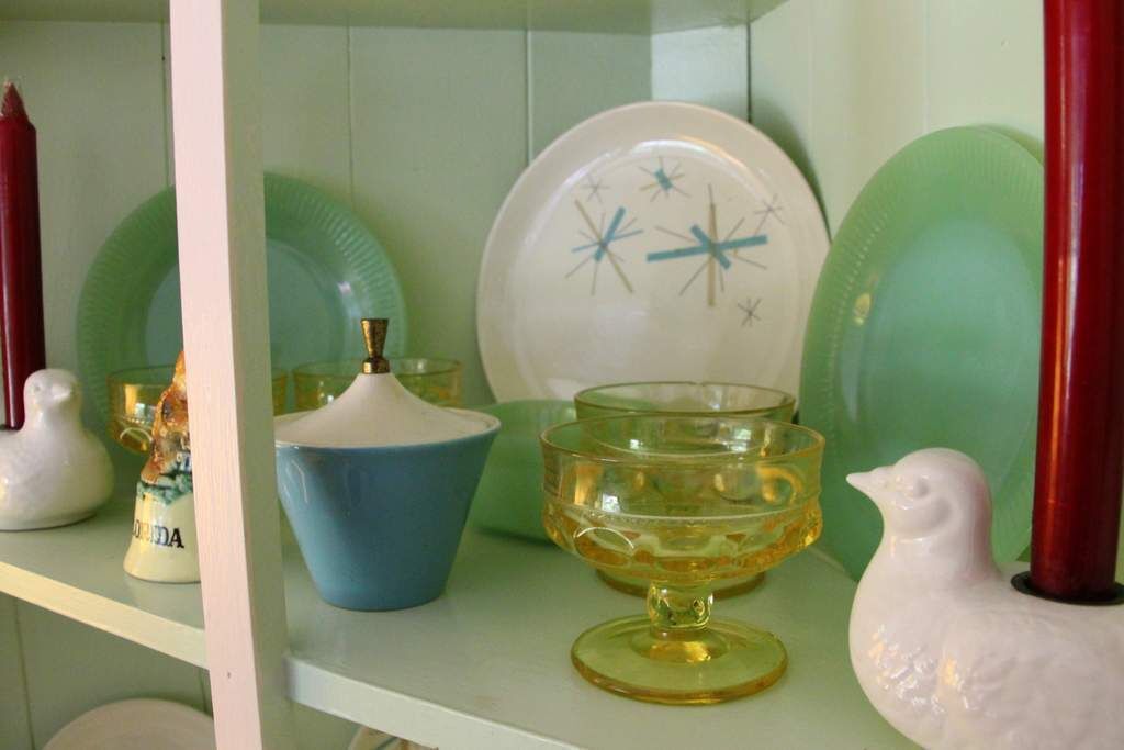 Une étagère avec divers plats en céramique et une figurine d’oiseau en céramique blanche.