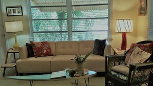 A living room with a sofa, a chair, a coffee table, and a lamp. - "OLD FLORIDA" RIVERSIDE POOL COTTAGE THAT TIME FORGOT (Sebastian)