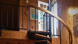 Un intérieur en bois avec un escalier en colimaçon, des murs en bois et une porte donnant sur une salle de bain.
